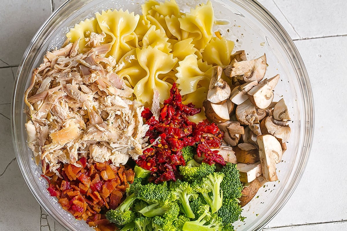 pasta, chicken and veggies in a glass mixing bowl