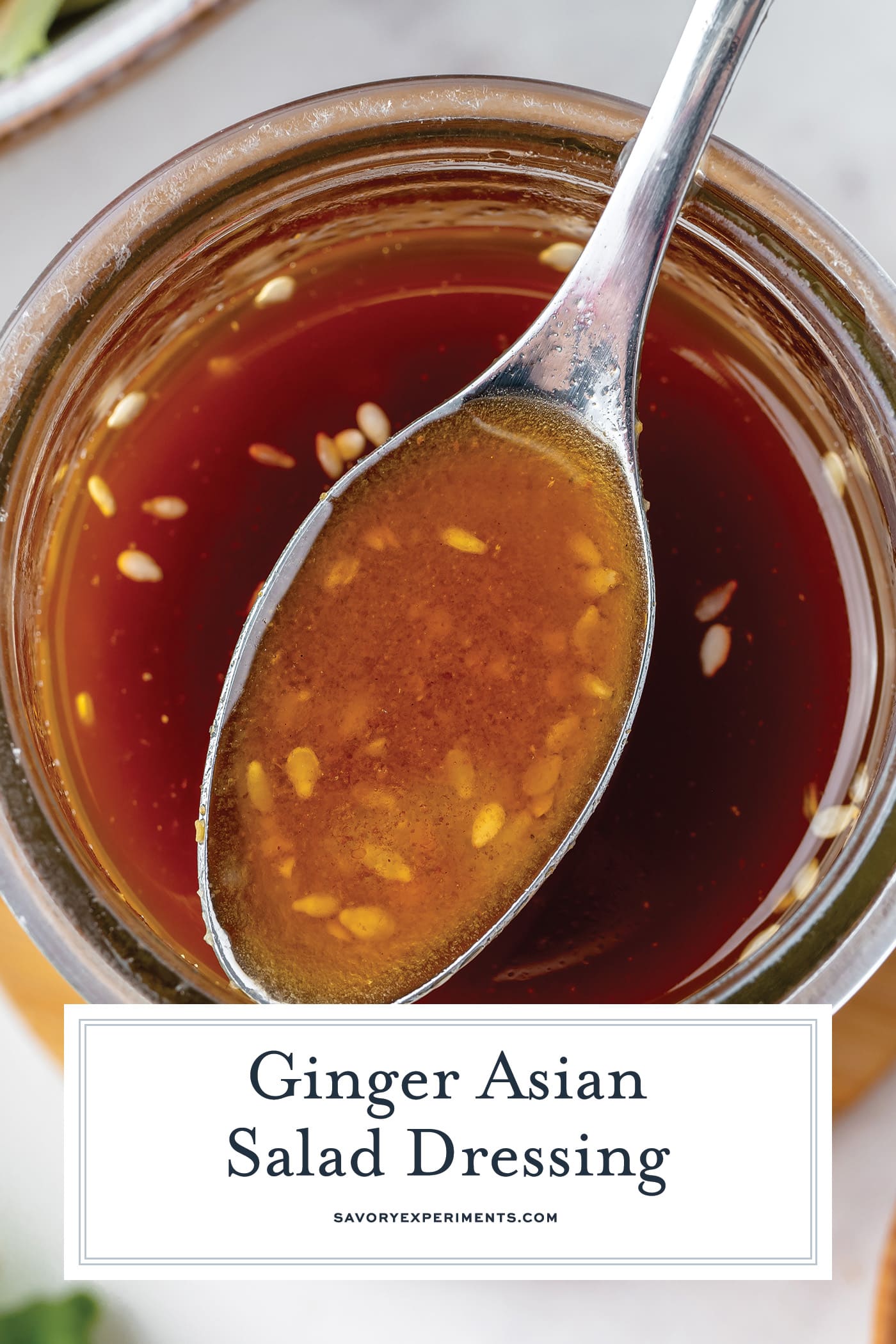overhead shot of spoon in asian ginger salad dressing with text overlay for pinterest