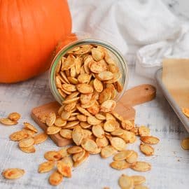 pumpkin seeds spilling out onto a white wood board
