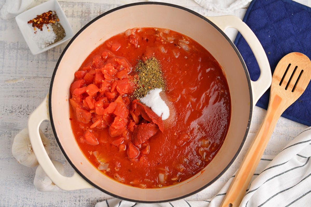 adding tomatoes and dried herbs to fra diavolo sauce