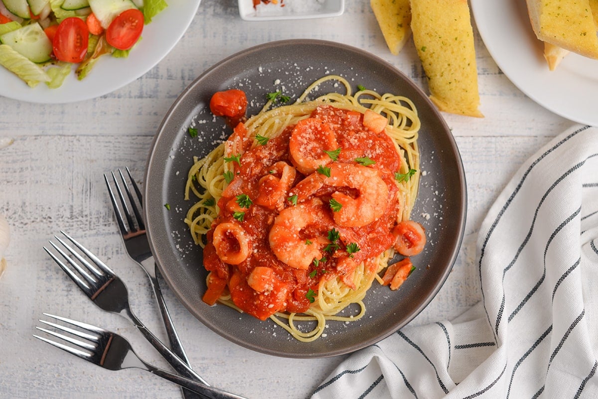 overhead of seafood fra diavolo with salad and breadsticks