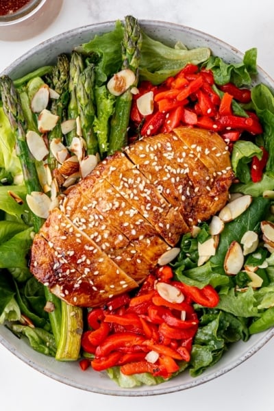 sticky chicken sliced on top of salad