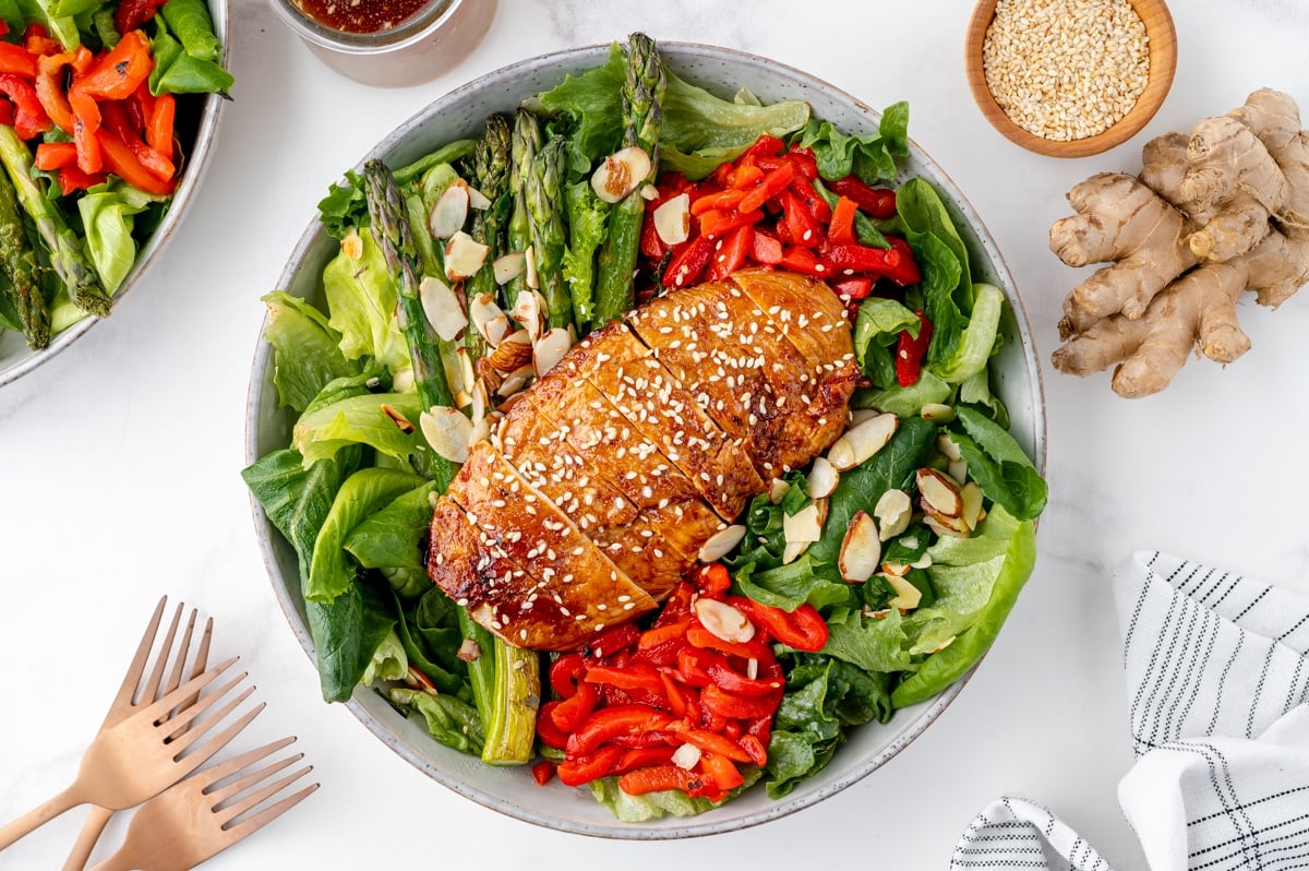 sticky chicken sliced on top of salad