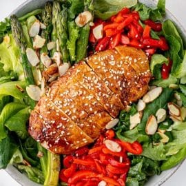 sticky chicken sliced on top of salad