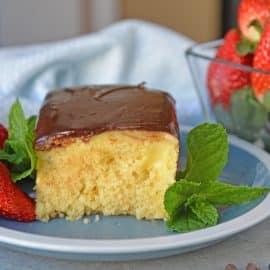 Boston Cream Poke Cake with Strawberries on a blue plate