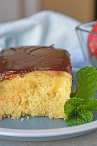 Boston Cream Poke Cake with Strawberries on a blue plate