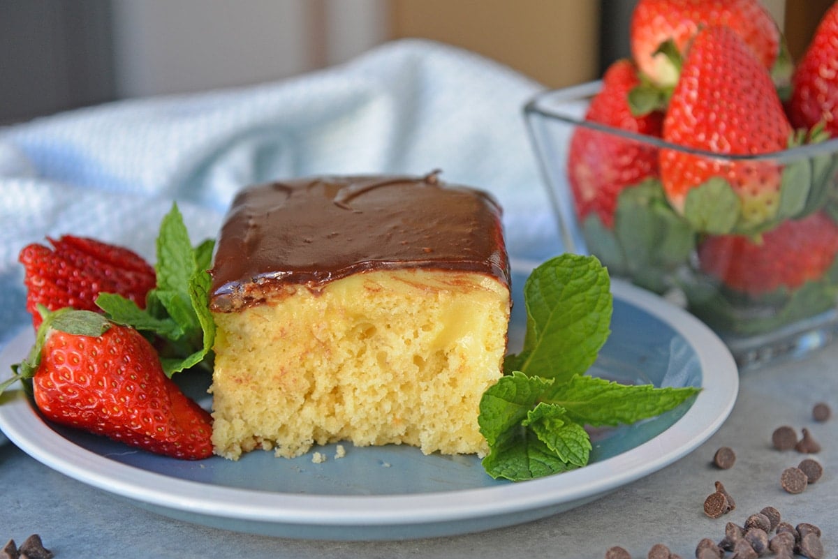 Boston Cream Poke Cake with Strawberries on a blue plate