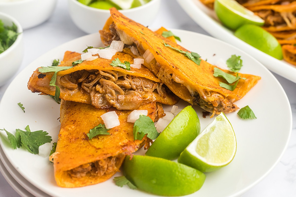 juicy chicken tacos on a small white serving plate with limes