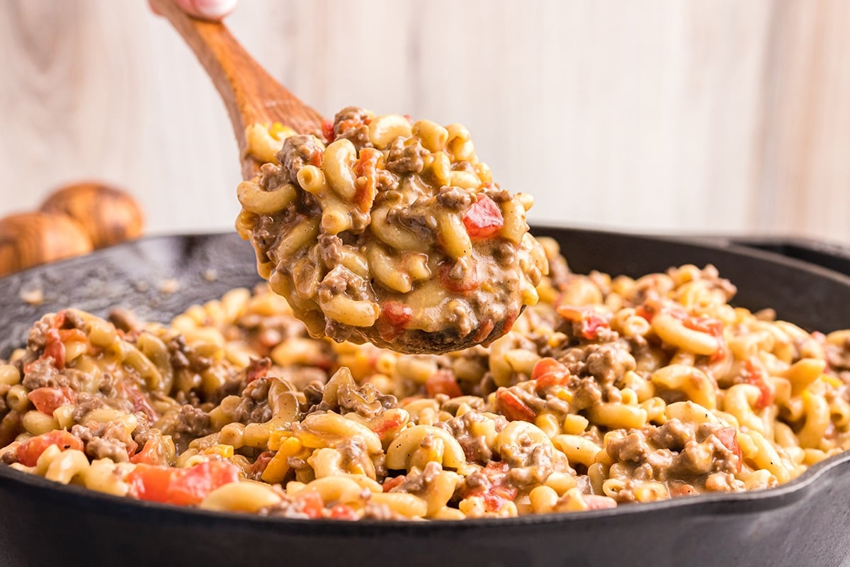 spoon dipping into skillet of cheeseburger mac