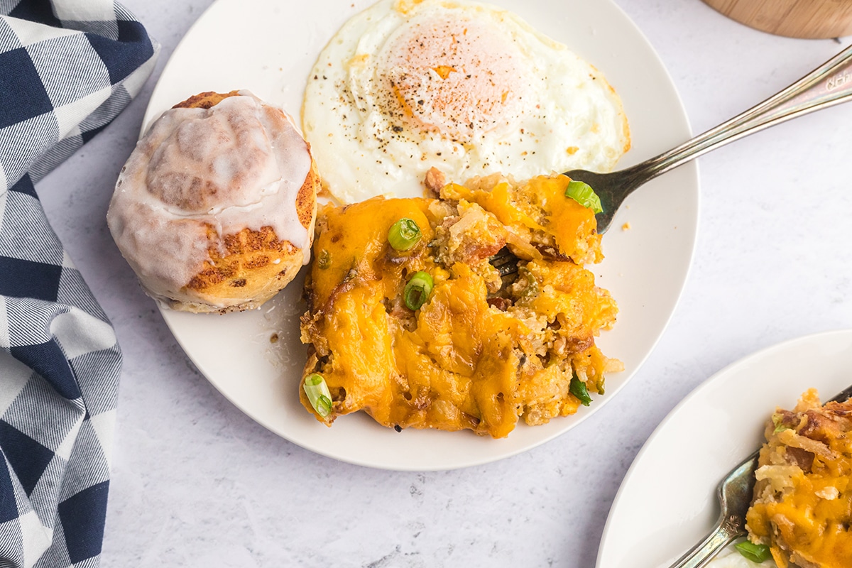 overhead shot of cheesy potatoes on plate with egg and cinnamon roll