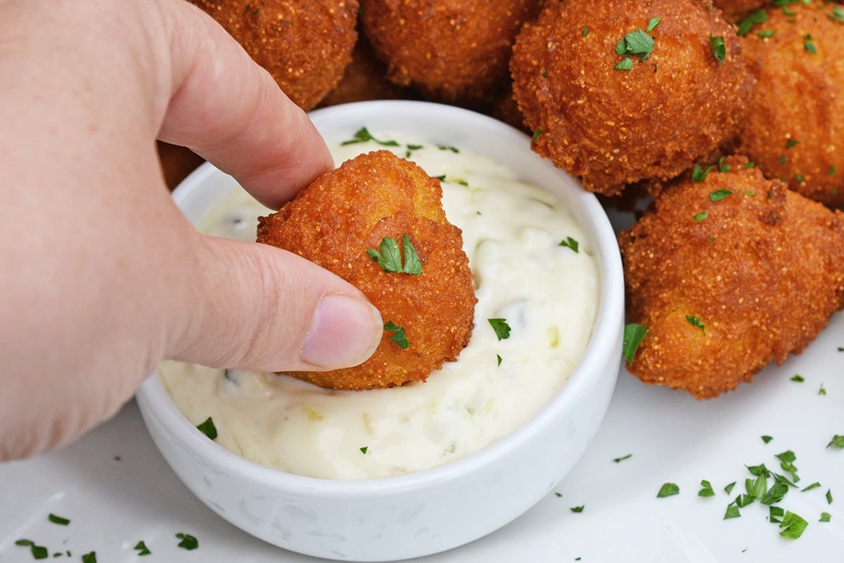 dipping hush puppies into dipping sauce