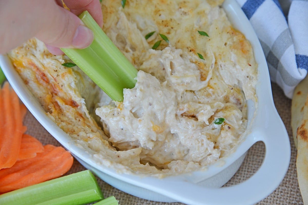 celery dipping into hot crab dip