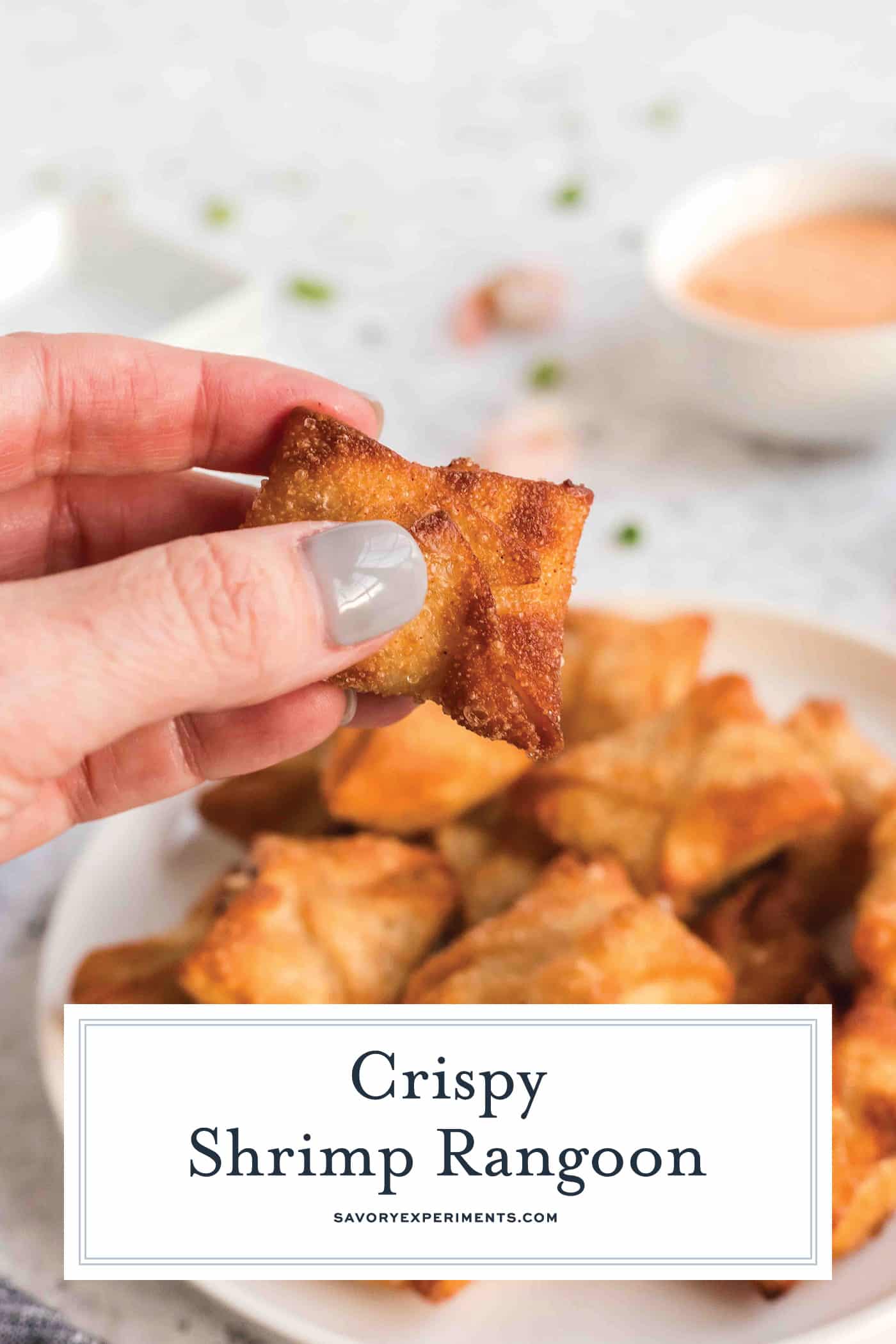 hand holding shrimp rangoon with text overlay for pinterest