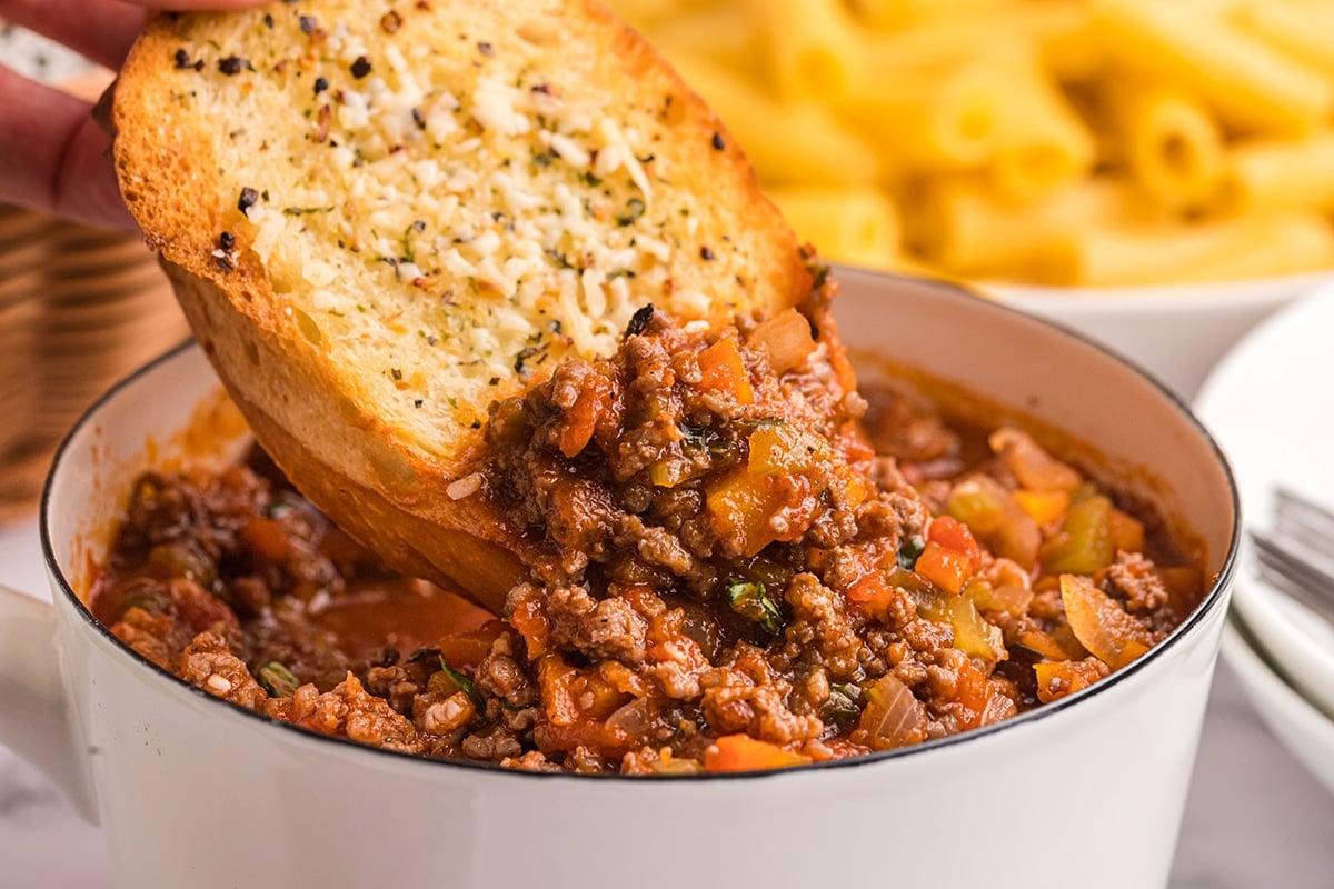 garlic bread dipping into meat sauce