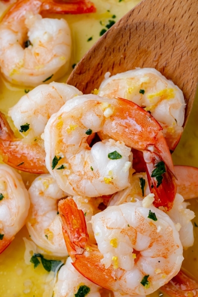 brined shrimp in a pan with a wooden spoon