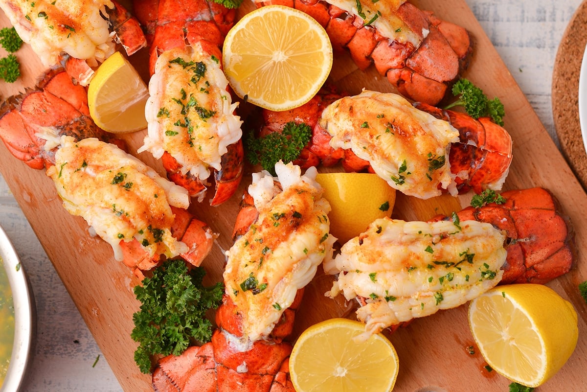 close up of lobster tails being served with fresh lemons