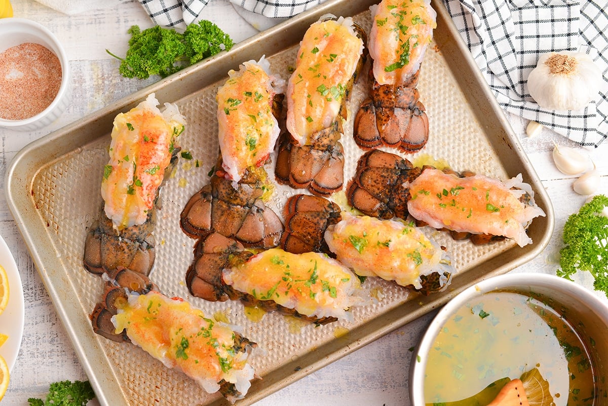 overhead of buttered lobster tails on a baking sheet