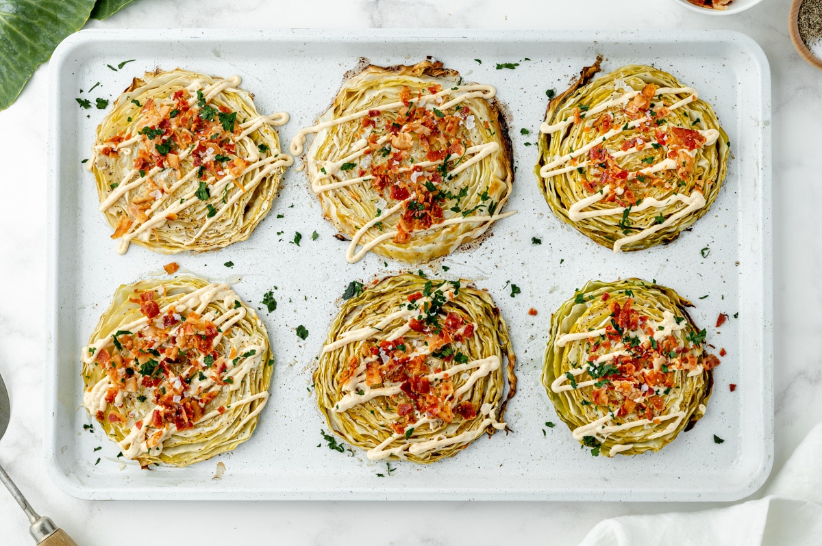 overhead shot of cabbage steaks topped with bacon and aioli