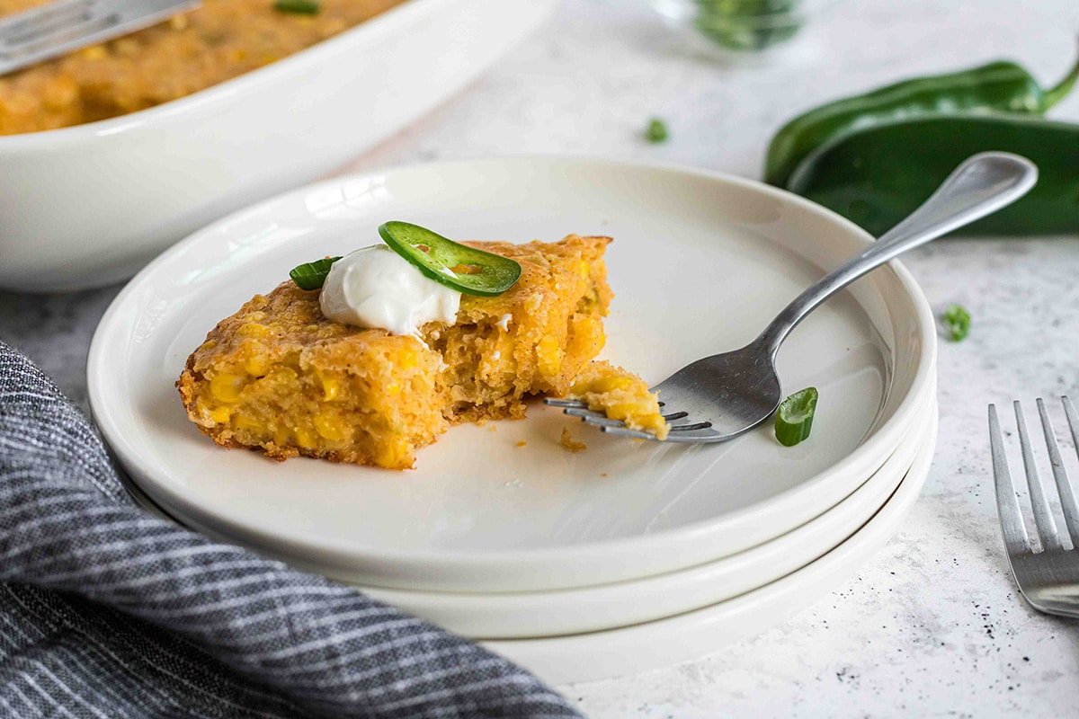 fork taking a bite of cornbread casserole on a plate