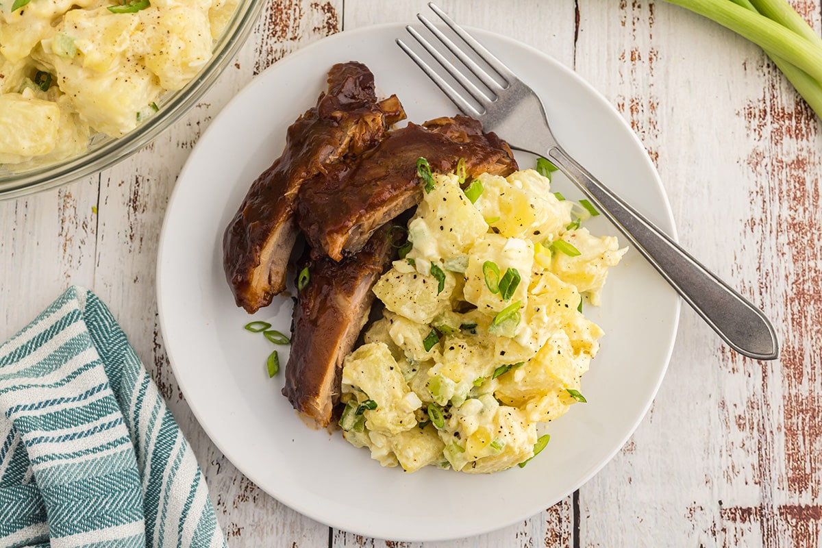 overhead shot of classic potato salad on plate with ribs