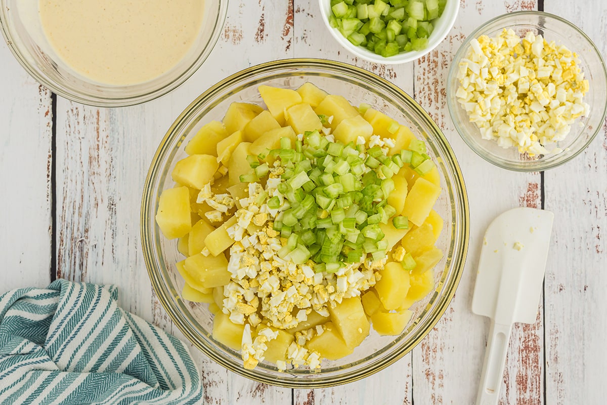eggs and celery added to bowl of potatoes