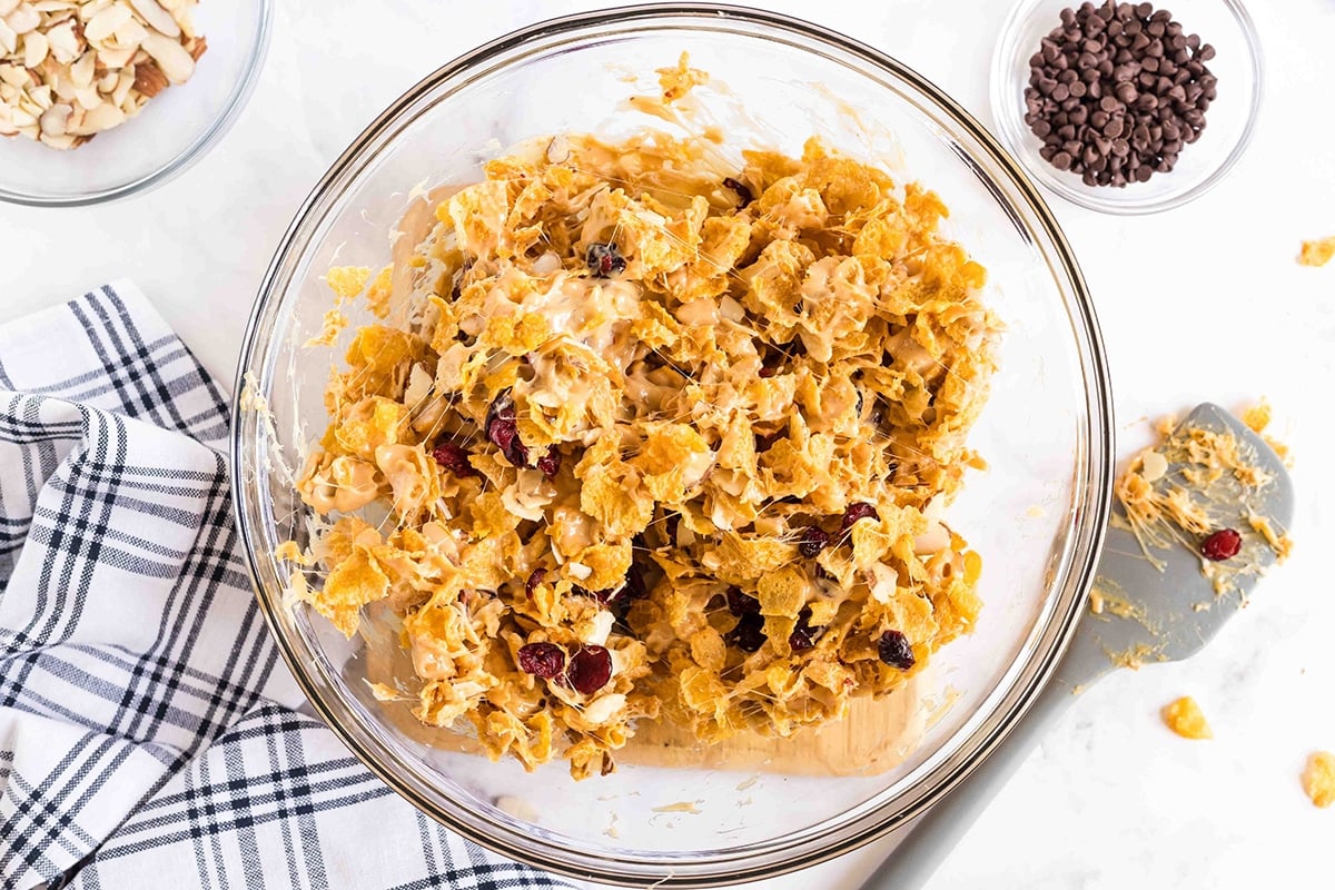 cereal mixture with peanut butter mixture in a large glass mixing bowl