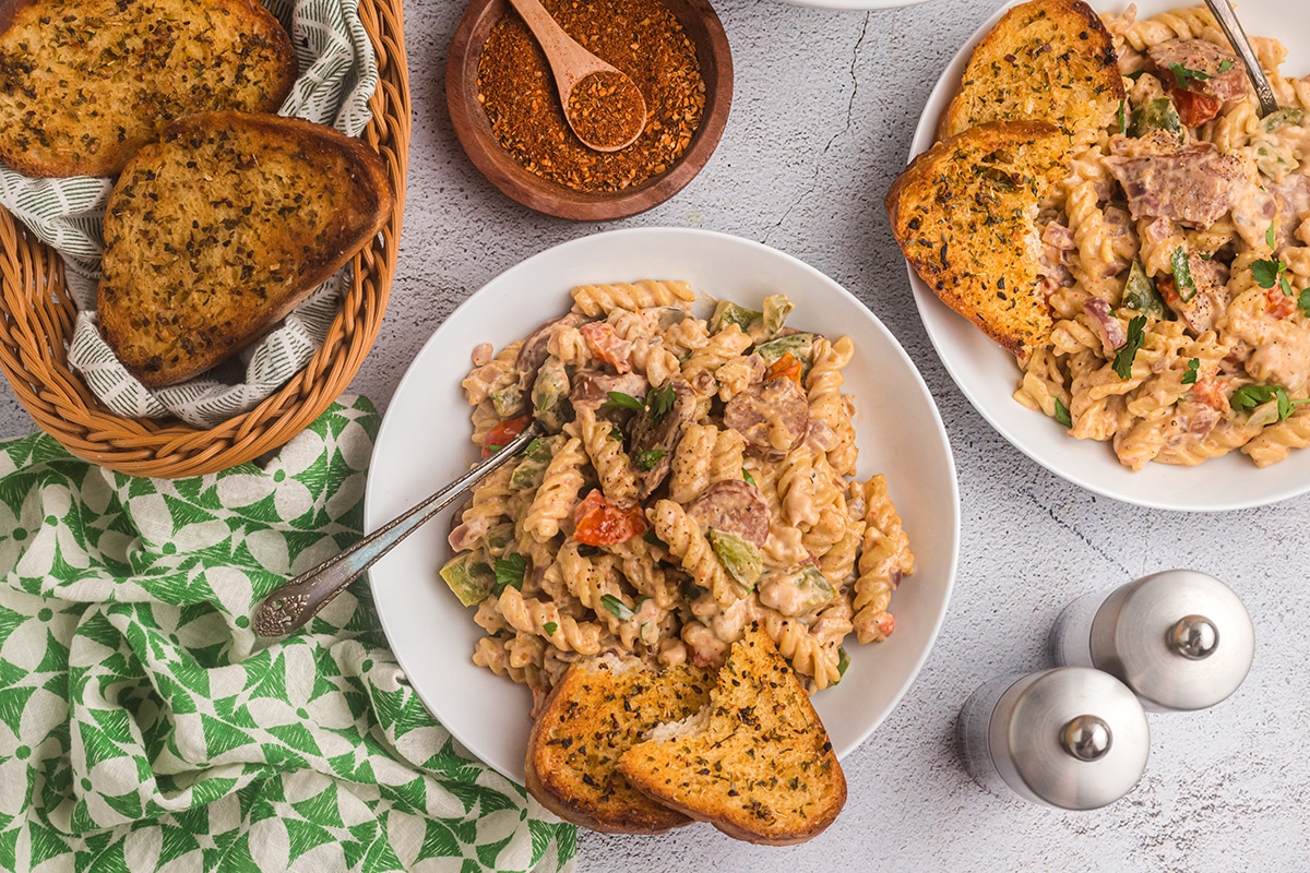 overhead shot of creamy cajun pasta in bowl with garlic bread