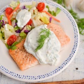angled shot of creamy dill salmon on a plate with salad