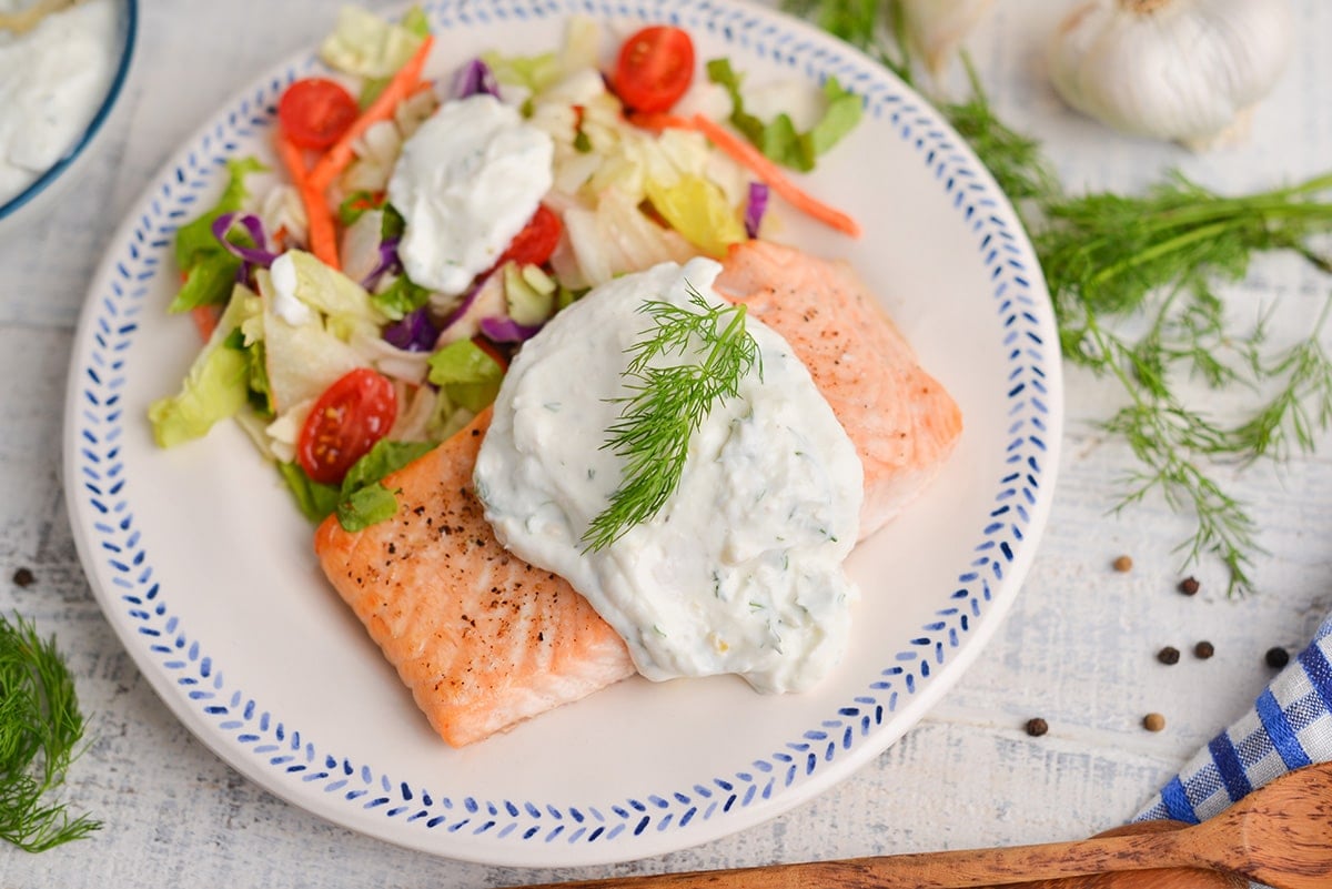 angled shot of creamy dill salmon on a plate with salad