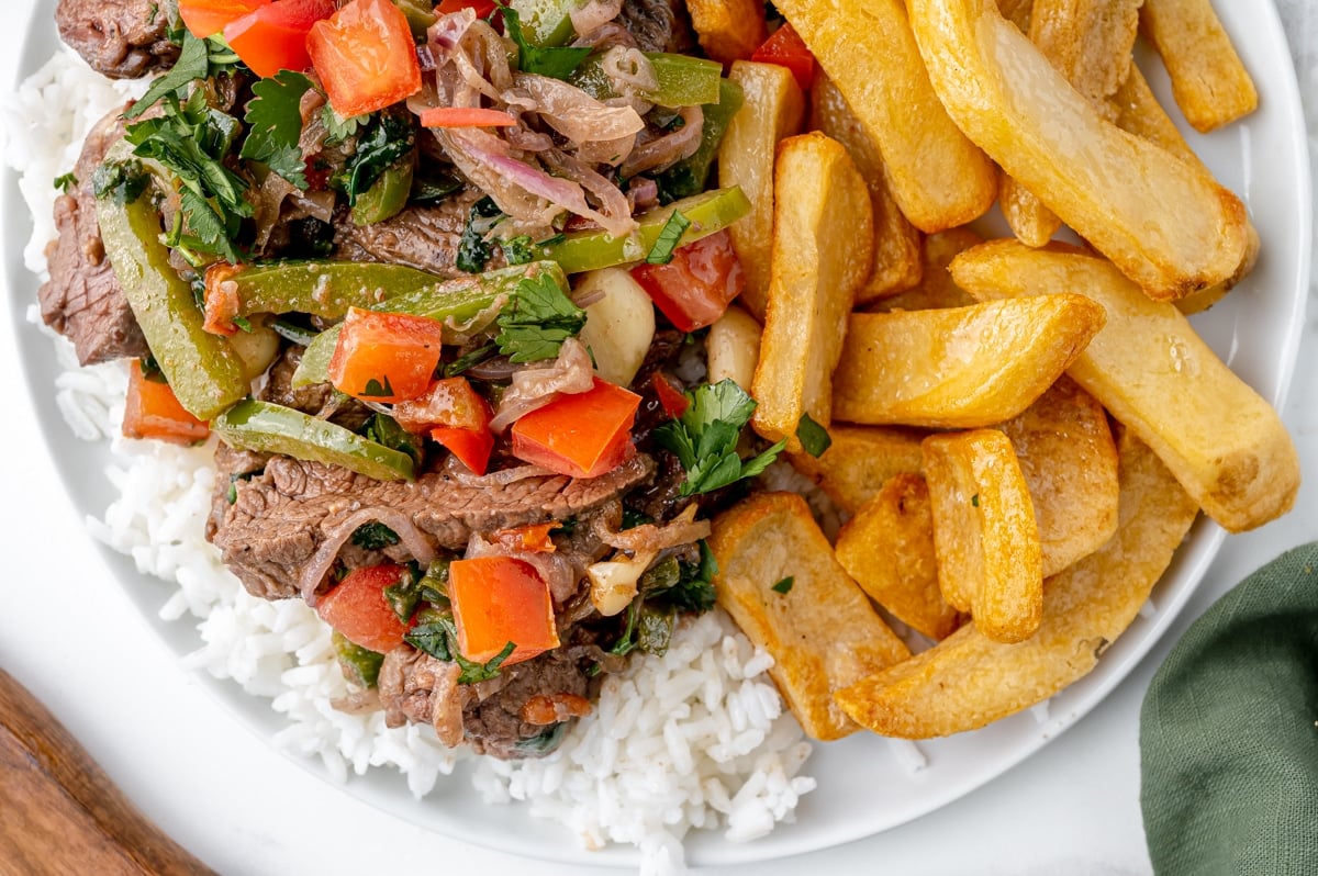 close up overhead of lomo saltado over rice with fries