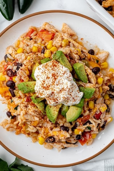 plate of chicken casserole topped with avocado and sour cream