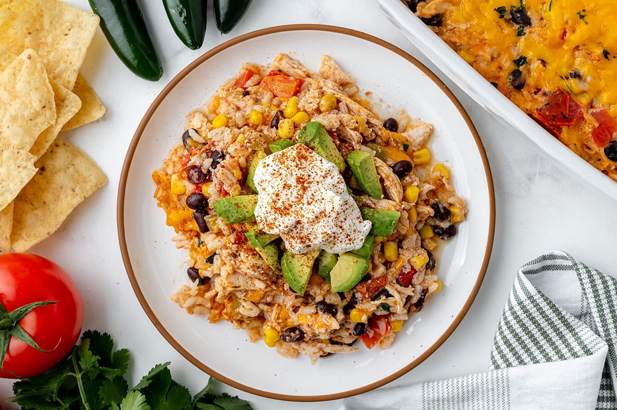 plate of chicken casserole topped with avocado and sour cream