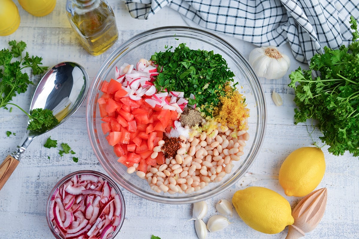 overhead of ingredients for navy bean salad in a glass mixing bowl