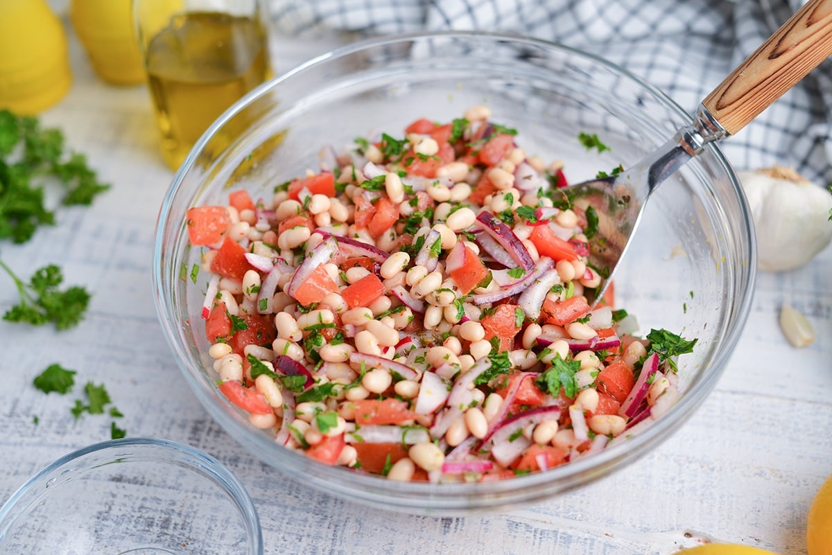 navy bean salad in a glass bowl with large serving spoon