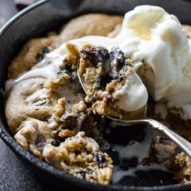 angled shot of spoon taking bite of oreo chocolate chip skillet cookie