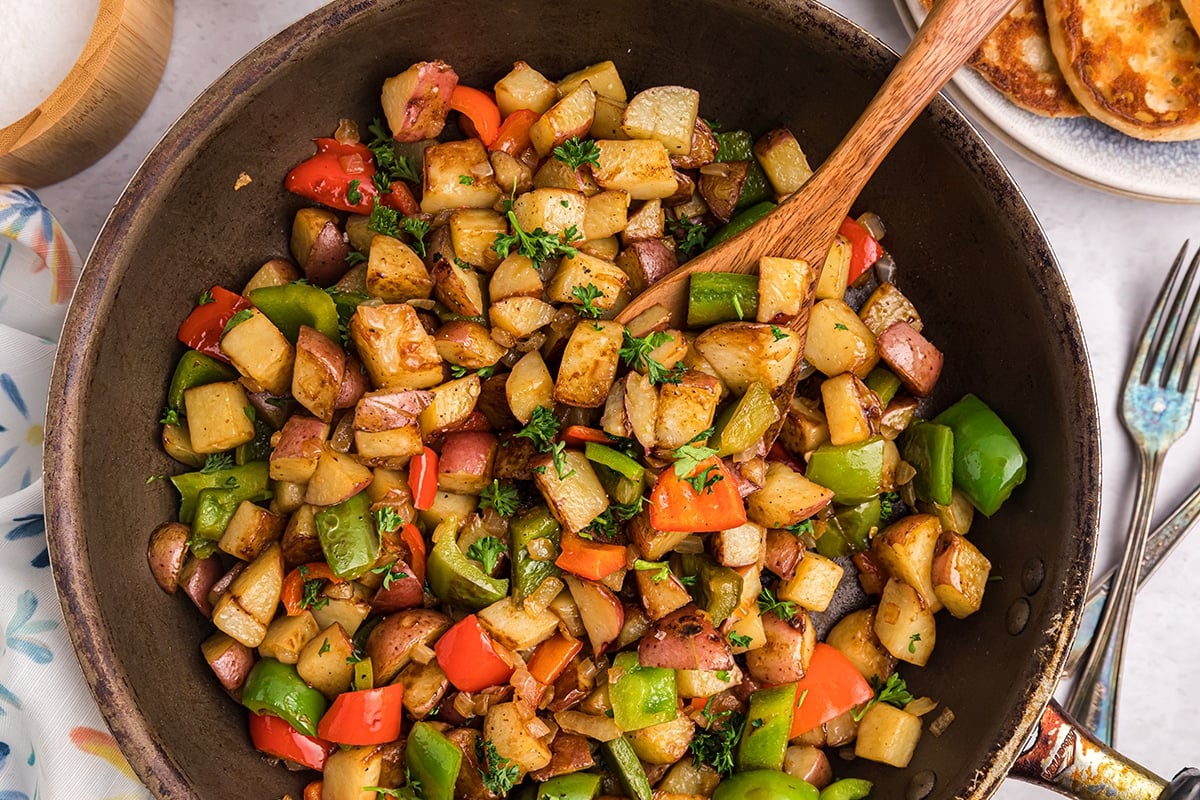 wooden spoon in pan of potatoes o'brien