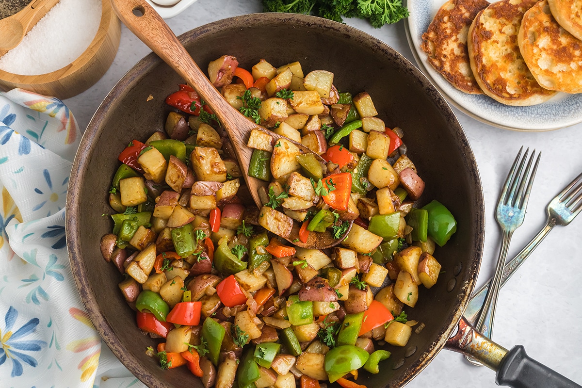 wooden spoon scooping potatoes out of a pan