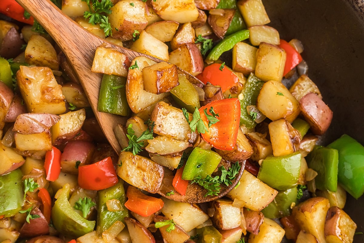 close up of wooden spoon full of potatoes o'brien