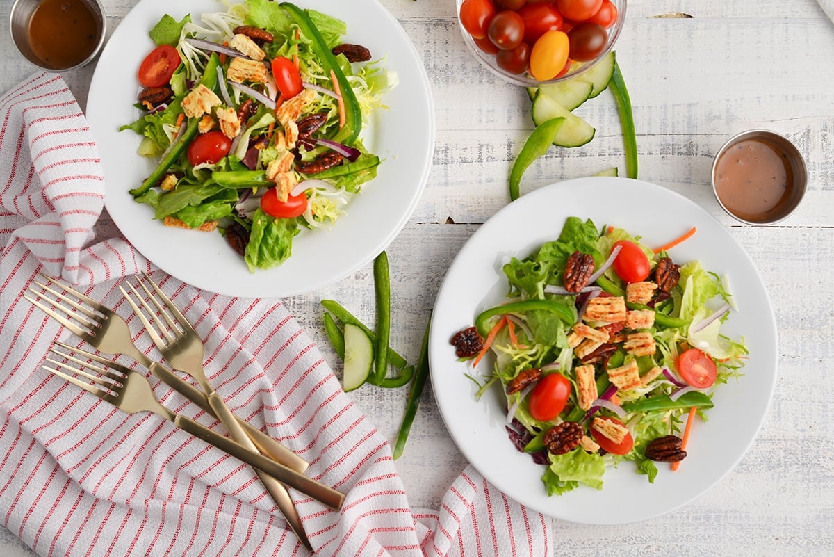 two undressed side salads with a red striped linen and veggies