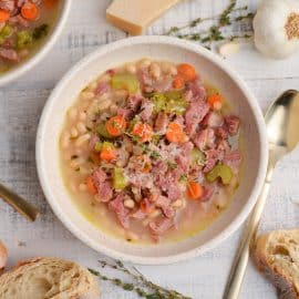 close up overhead of white bean and ham soup with gold spoons