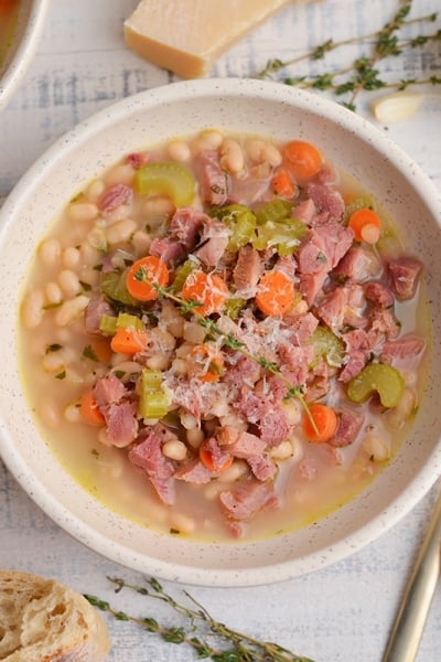 close up overhead of white bean and ham soup with gold spoons