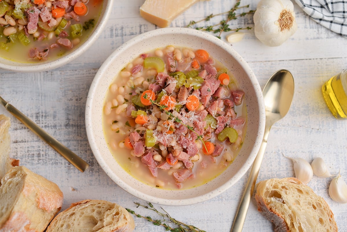 close up overhead of white bean and ham soup with gold spoons