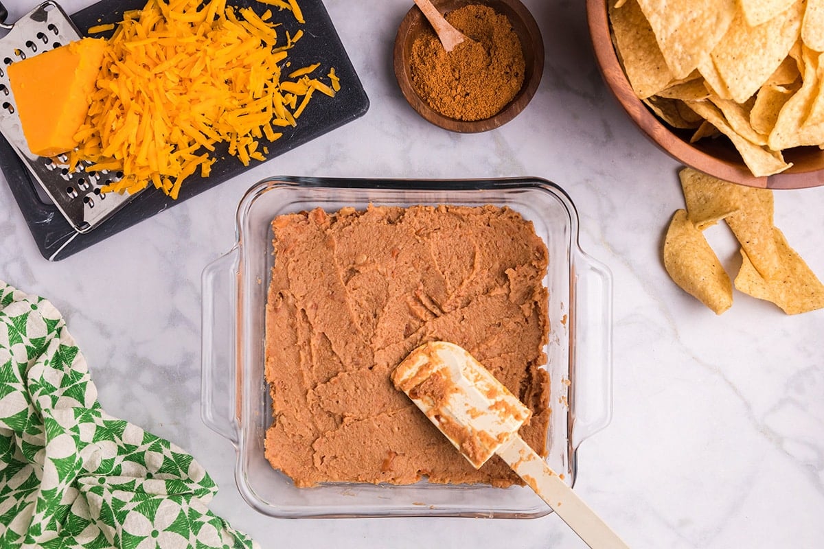 refried beans spread into glass dish