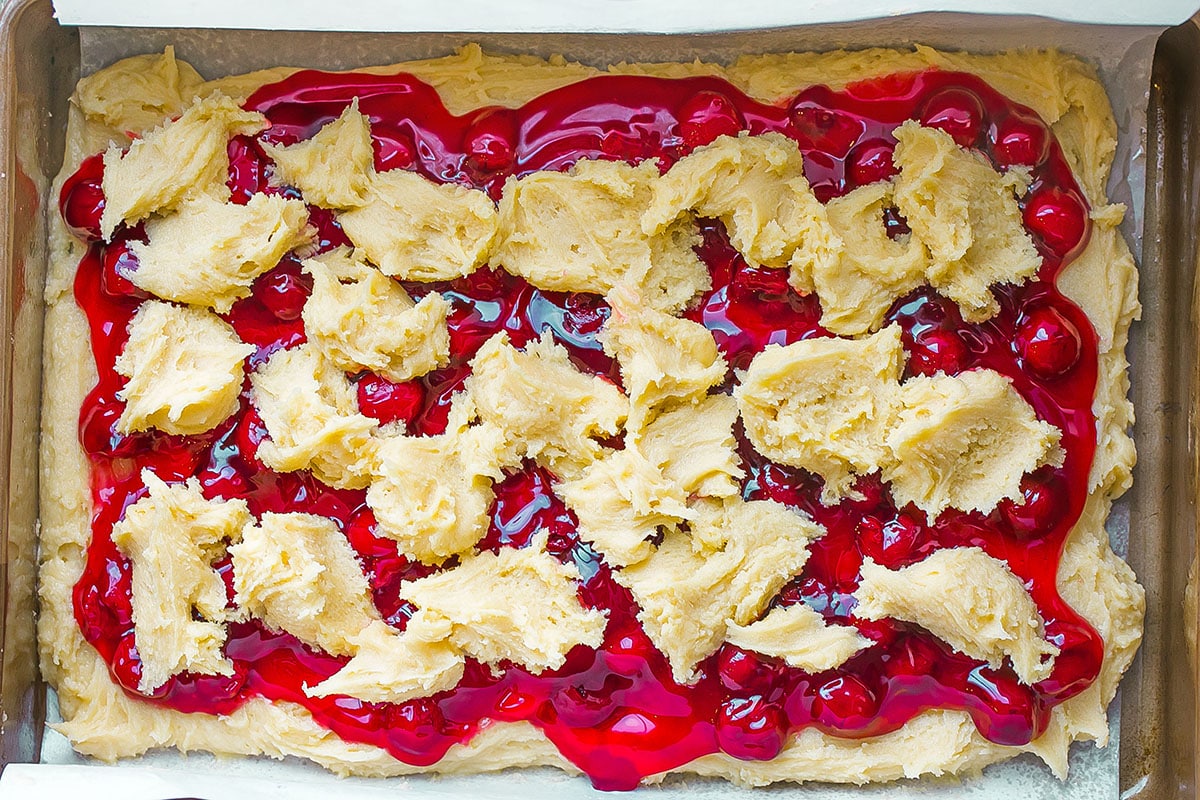 dollops of batter on cherry pie filling in a baking dish