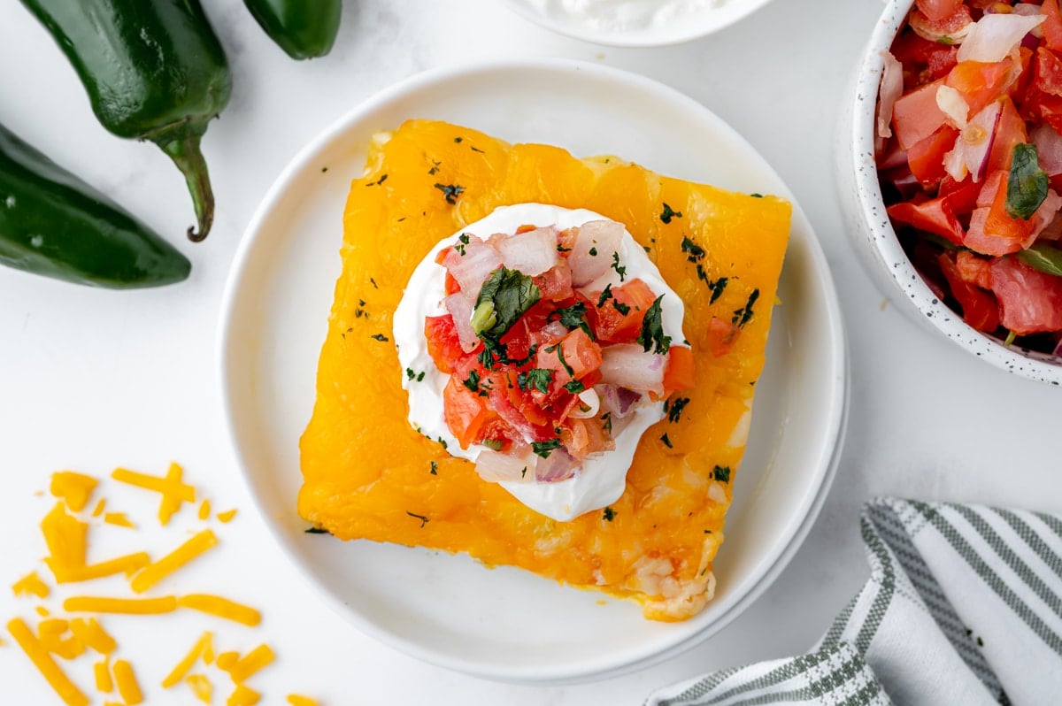 overhead of chile relleno casserole with pico de gallo with sour cream