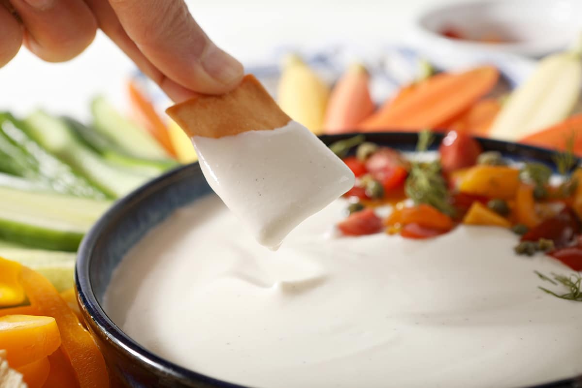 pita chip dipping into greek feta dip