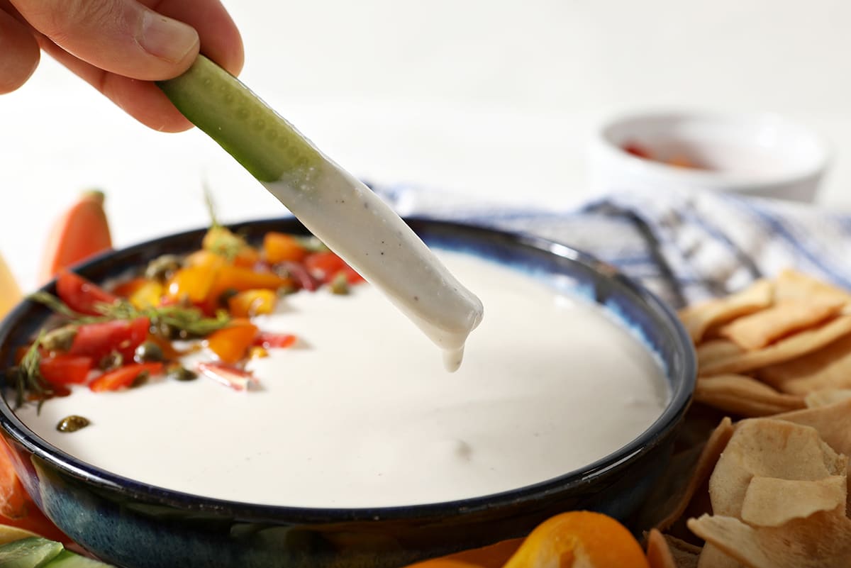 cucumber dipping into bowl of greek feta dip