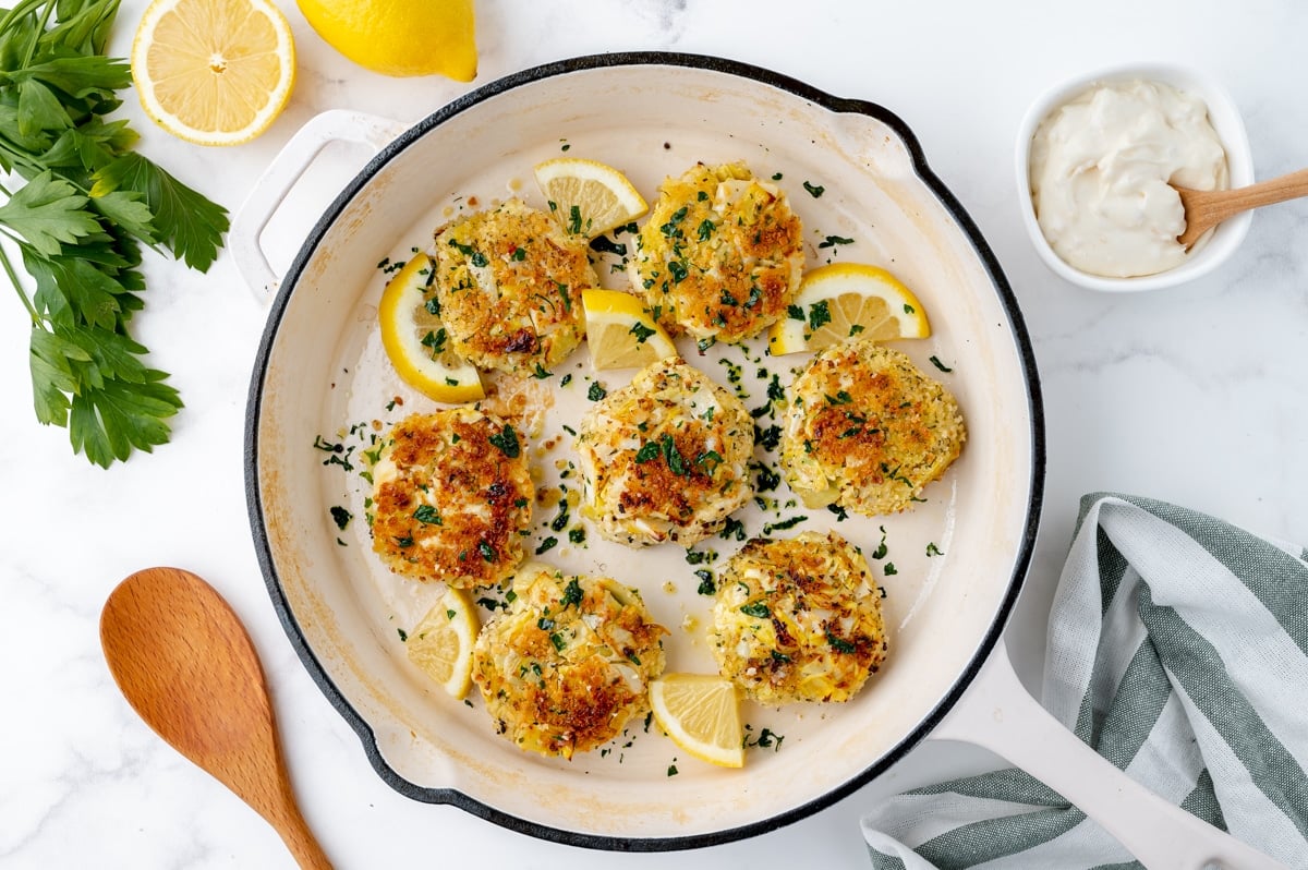 hearts of palm cakes in pan with lemon wedges