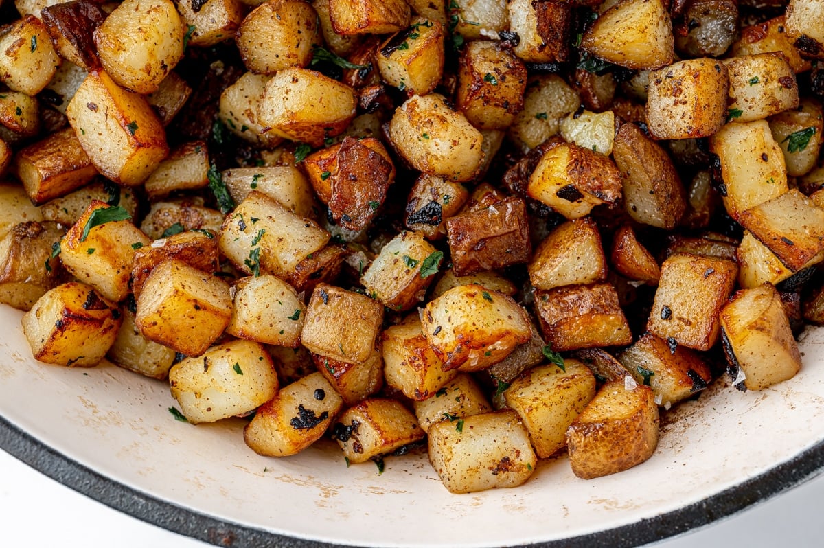 close up of brown fried potatoes in a white skillet