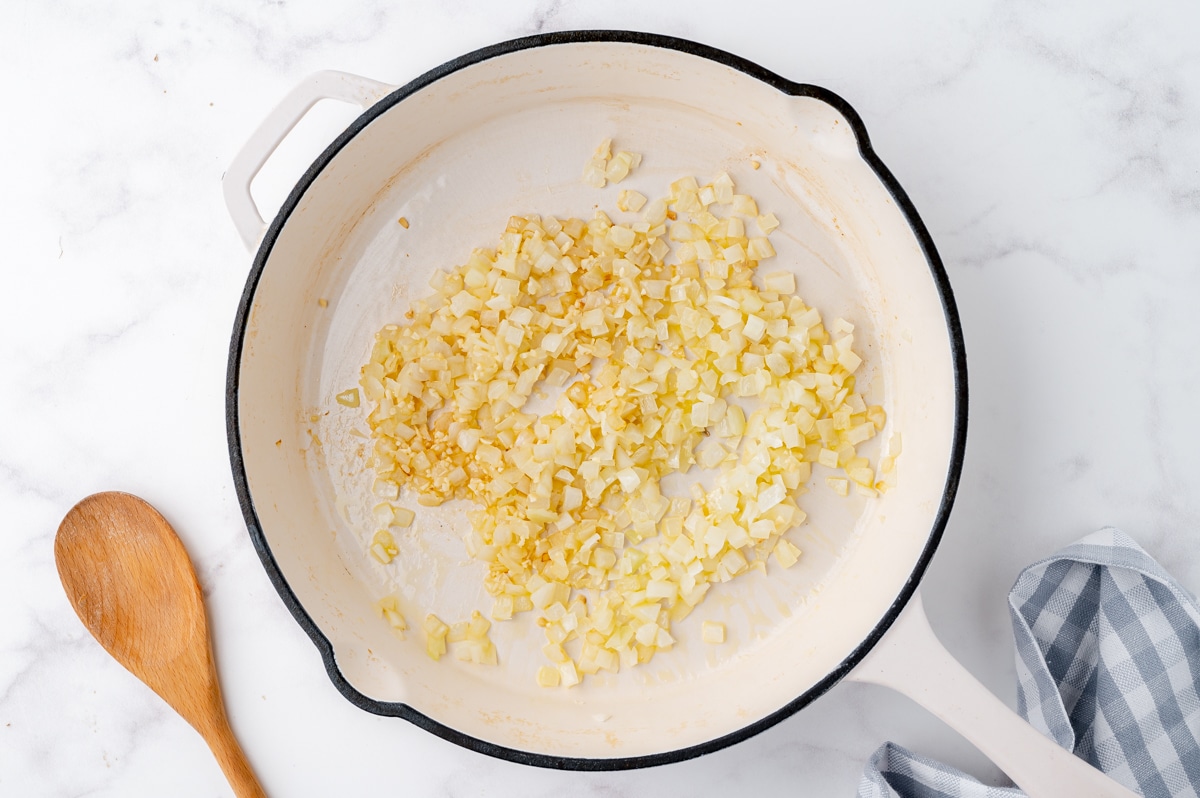 onion and garlic in a white ceramic frying pan